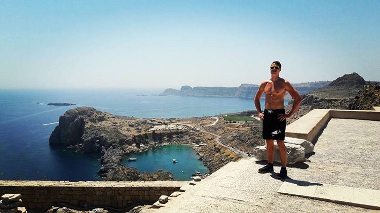 Sporttienergiaa voittajakuva @turovaisanen, julkaistu Instagramissa. Mies seisoo aurinkoisella mäellä, taustalla meri