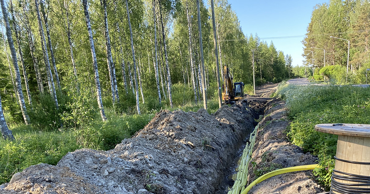 Kaivinkone ja kaivuutyömaa, kaapelia kaivetaan maan alle maantien viereen